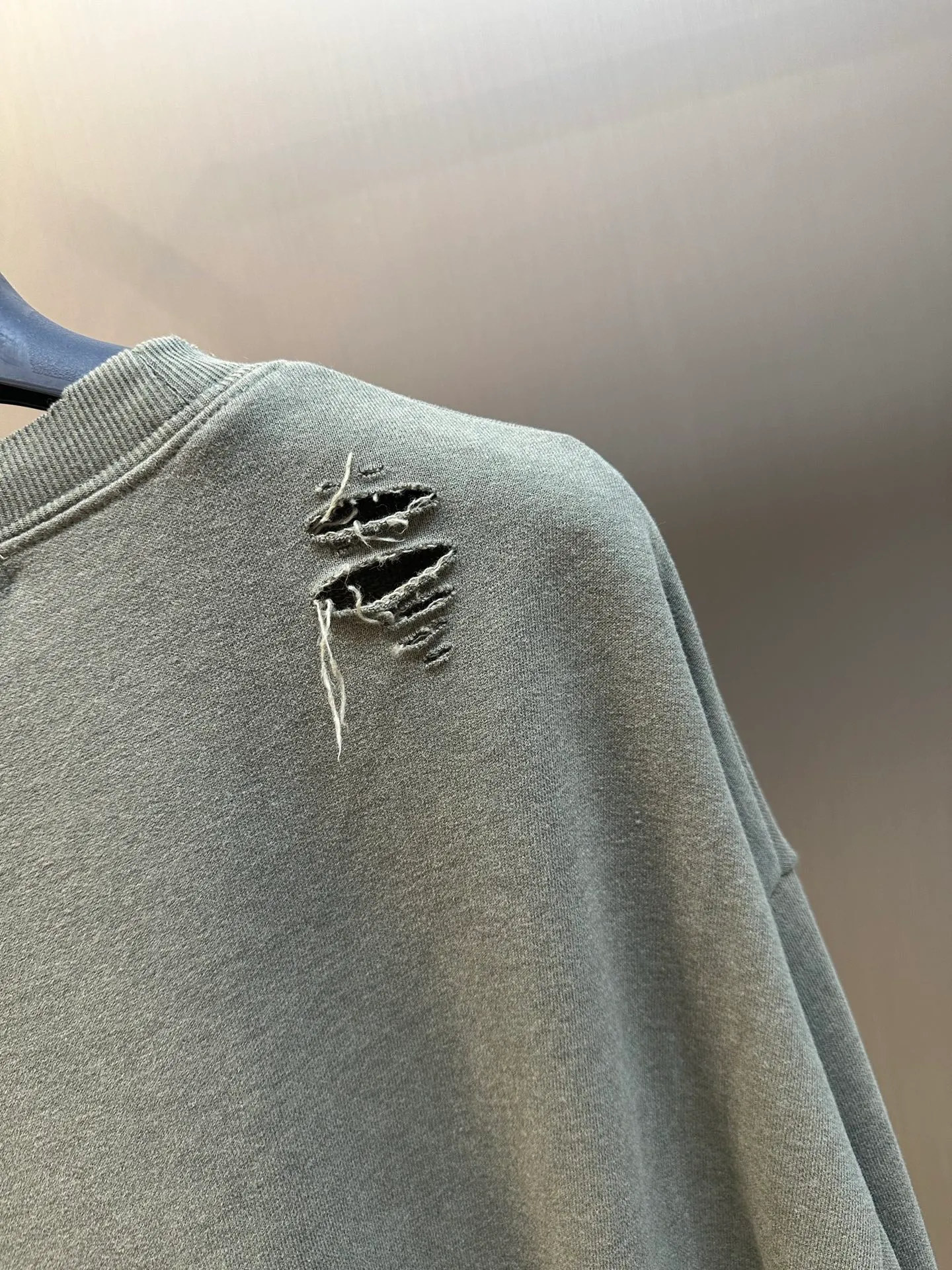 Ac Studios ripped distressed logo sweatshirt, custom dyed 1:1 gray green soft cotton sweatshirt material, the top fabric and terry bottom are the same color configuration, the market fabric In Stock has a different color on the top and bottom, which does not match the original! The minimum order quantity of fabric is 2 tons, and the fabric manufacturing process alone takes 45 days! The unruly soul of Ac Studios is engraved on the chest. The ingenious integration of hole elements and wanton swaying on the Gray canvas is a deliberate rebellion and a break away from the shackles of tradition. It is unique in the wave of the trend. It uses glue printing. The chest printing has been modified three times with the film screen. The glue liquid paint is used to print the pattern on the fabric, and the fabric is baked to fix the printing pattern. Many parts of the body of the garment are frayed and worn at regular intervals by purely artificial means, and marks are manually brushed to add texture and depth to the surface of the garment to imitate the texture of natural wear and tear. size：s m l xl